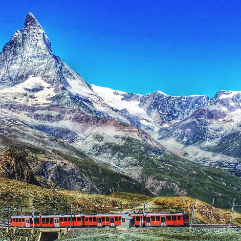 Red toy train in hills – classic travel tour
